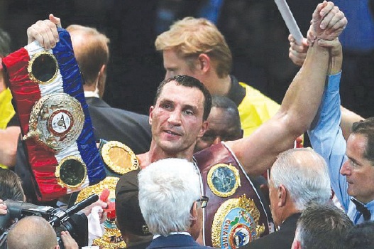 Volodymyr Klitschko celebrates with his multiple world titles after beating Alexander Povetkin